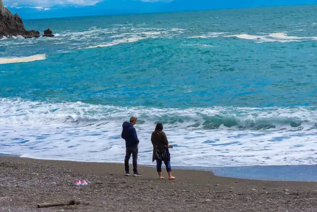 Two people standing on the beach at Atrani, watching the waves come in.